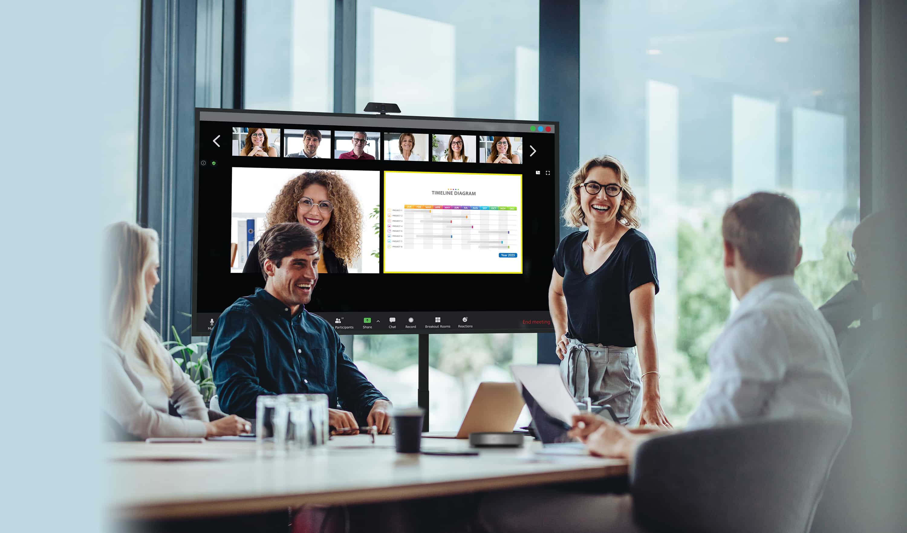 Des hommes d'affaires organisant une réunion avec des collaborateurs physiquement présents regardent un écran Série N Optoma tandis que leurs collègues à distance sont affichés à l'écran avec le contenu qu'ils partagent.